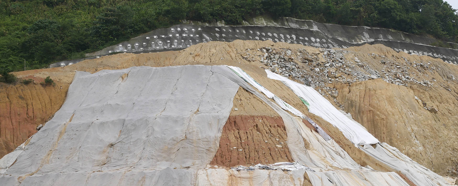 Geotextile fabric sheets covering a steep dirt hillside for erosion control