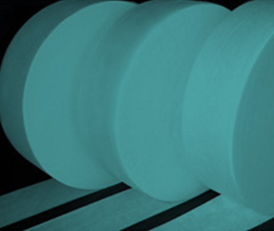 Gulungan besar kain nonwoven berwarna cyan di fasilitas manufaktur