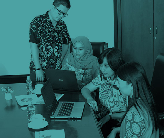 Tim yang terdiri dari empat profesional sedang berkolaborasi mengelilingi laptop di ruang rapat