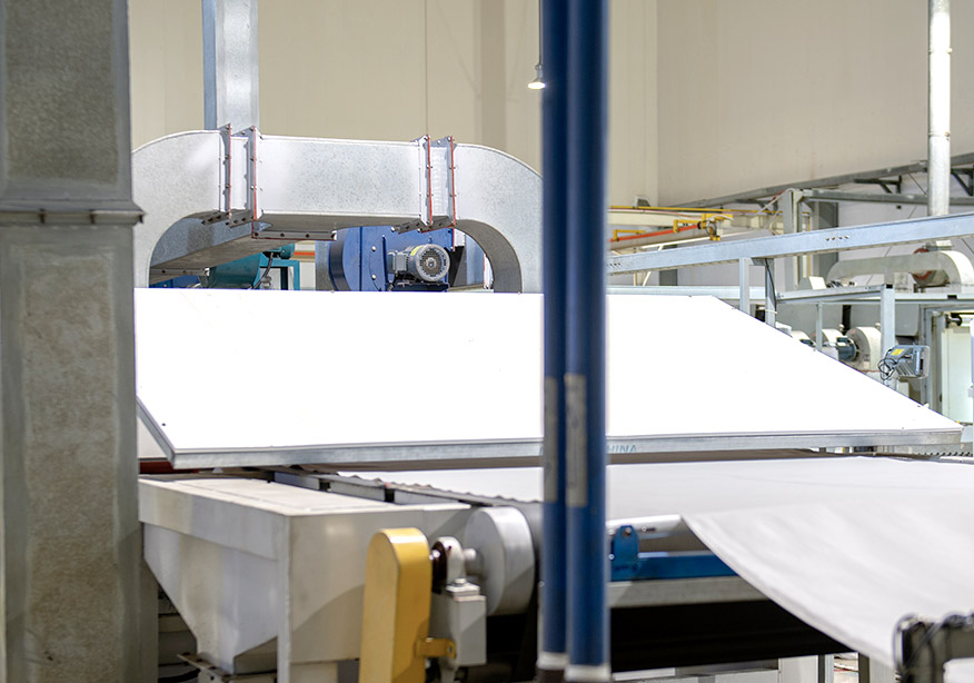 White material being processed on a conveyor belt in a manufacturing facility