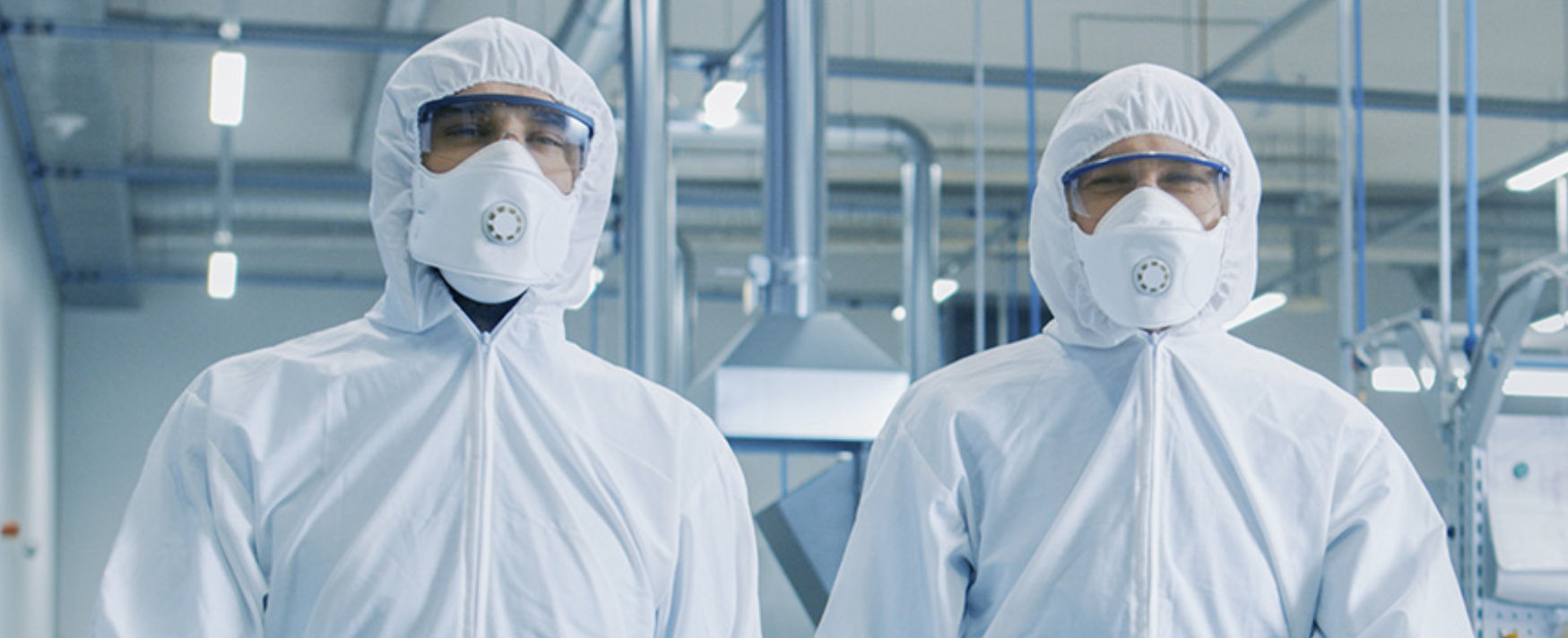 Two workers wearing full white protective hazmat suits made of nonwoven fabric