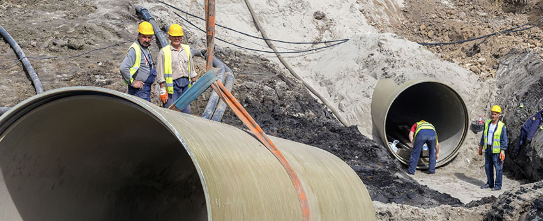 Workers at a construction site laying large-diameter FRP pipes