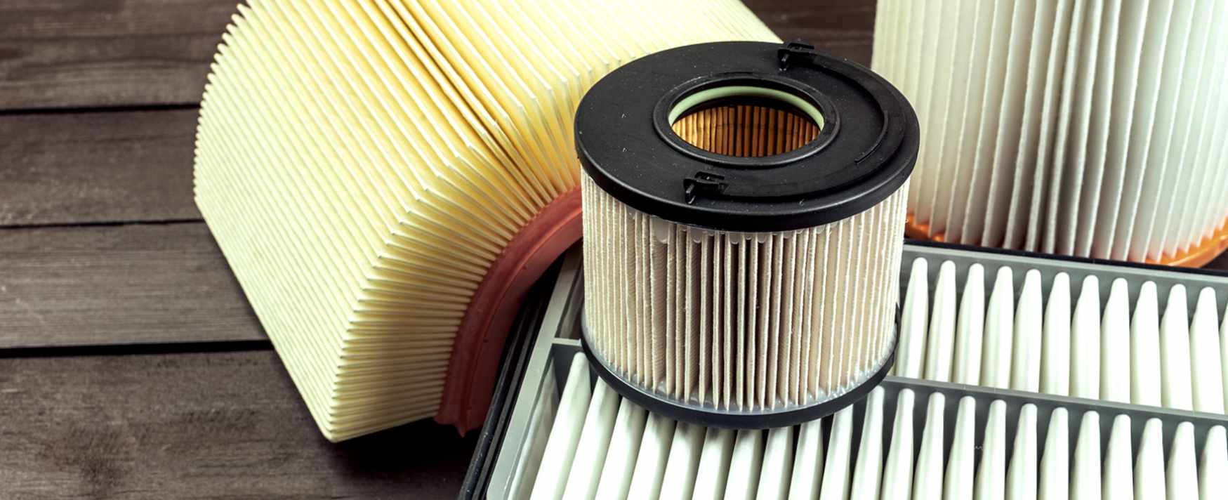 Collection of various cylindrical and rectangular air filters on a wooden surface