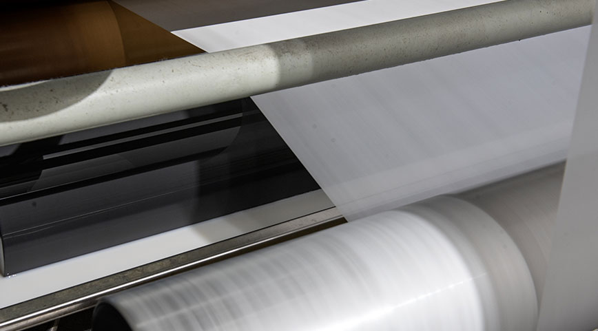 Smooth white nonwoven fabric passing over high-speed spinning rollers